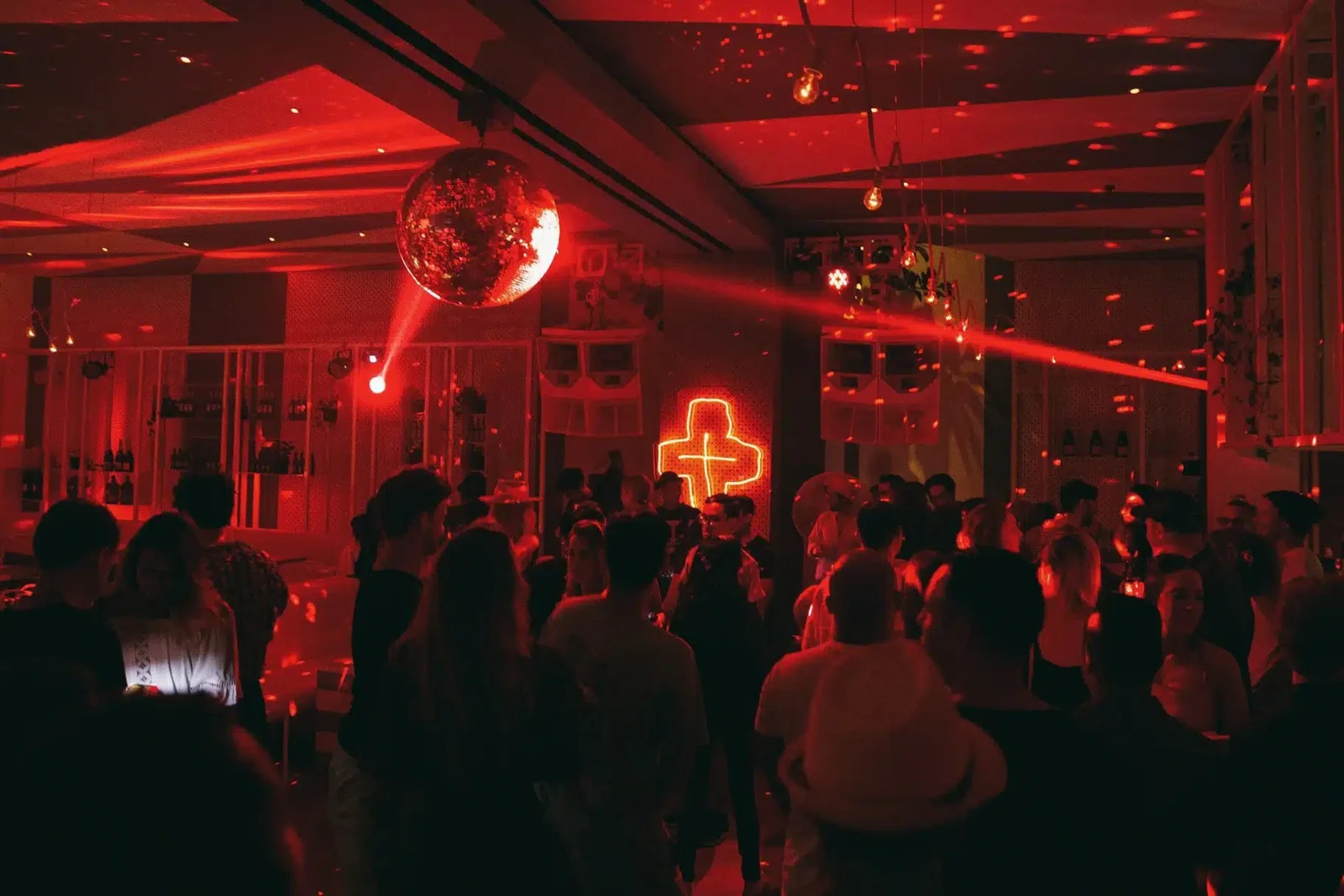 Guests dancing beneath red lights and a mirrored disco ball at Da Maria.