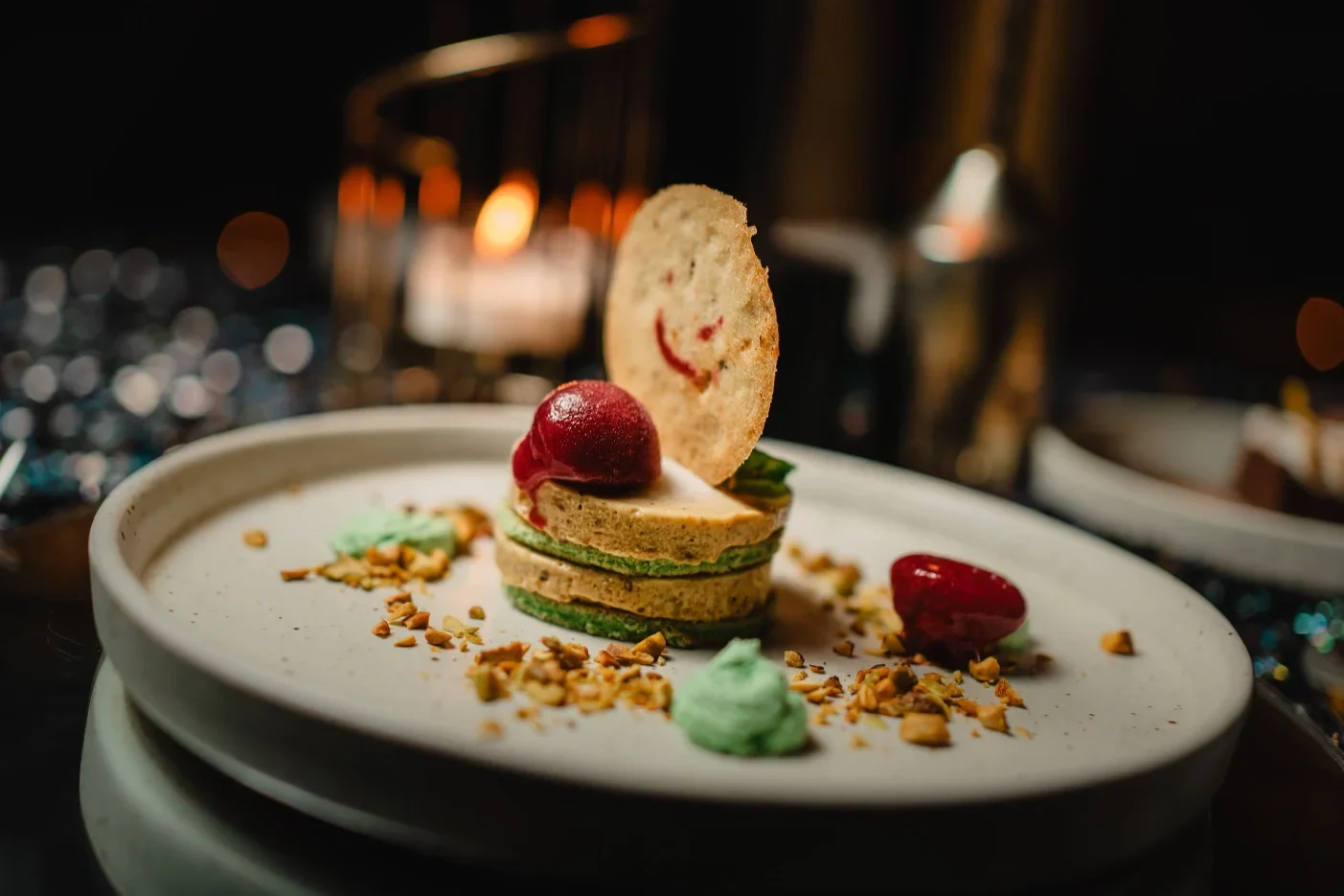A layered plated dessert with berries and a crisp garnish at Akar