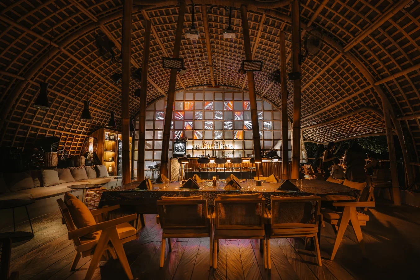 Warmly lit bar and dining seats beneath Akar’s curved bamboo ceiling