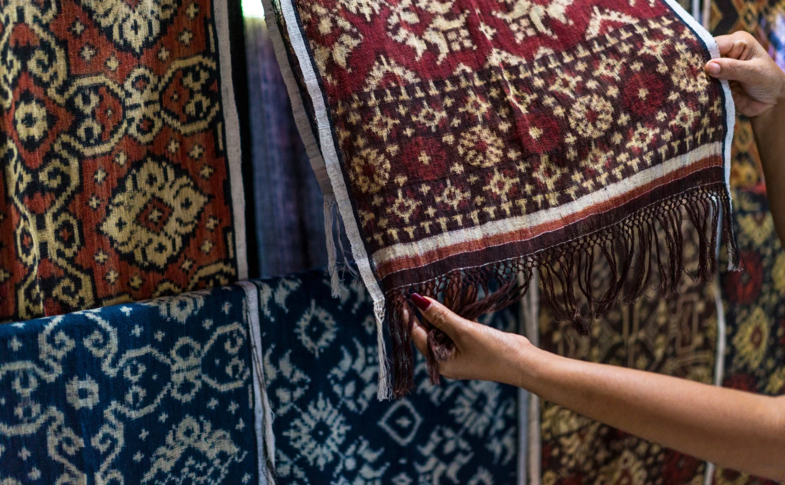 Hands holding a patterned woven textile in an Amankila cultural experience photograph.