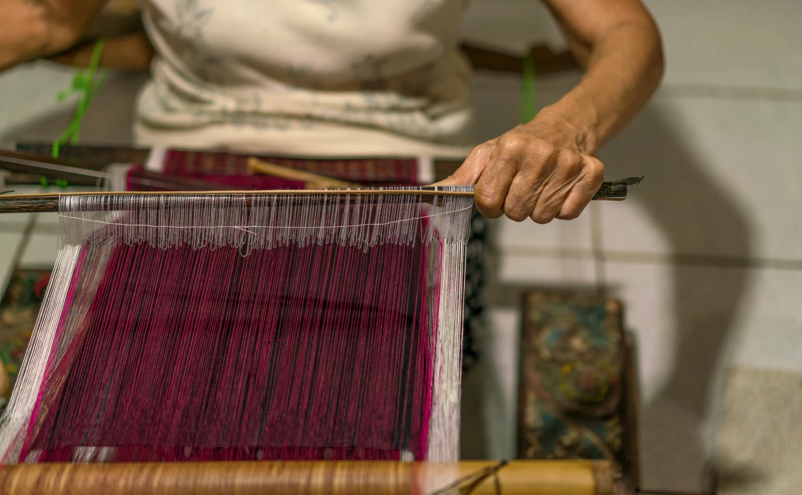 An artisan working red thread on a loom in an Amankila cultural experience photograph.