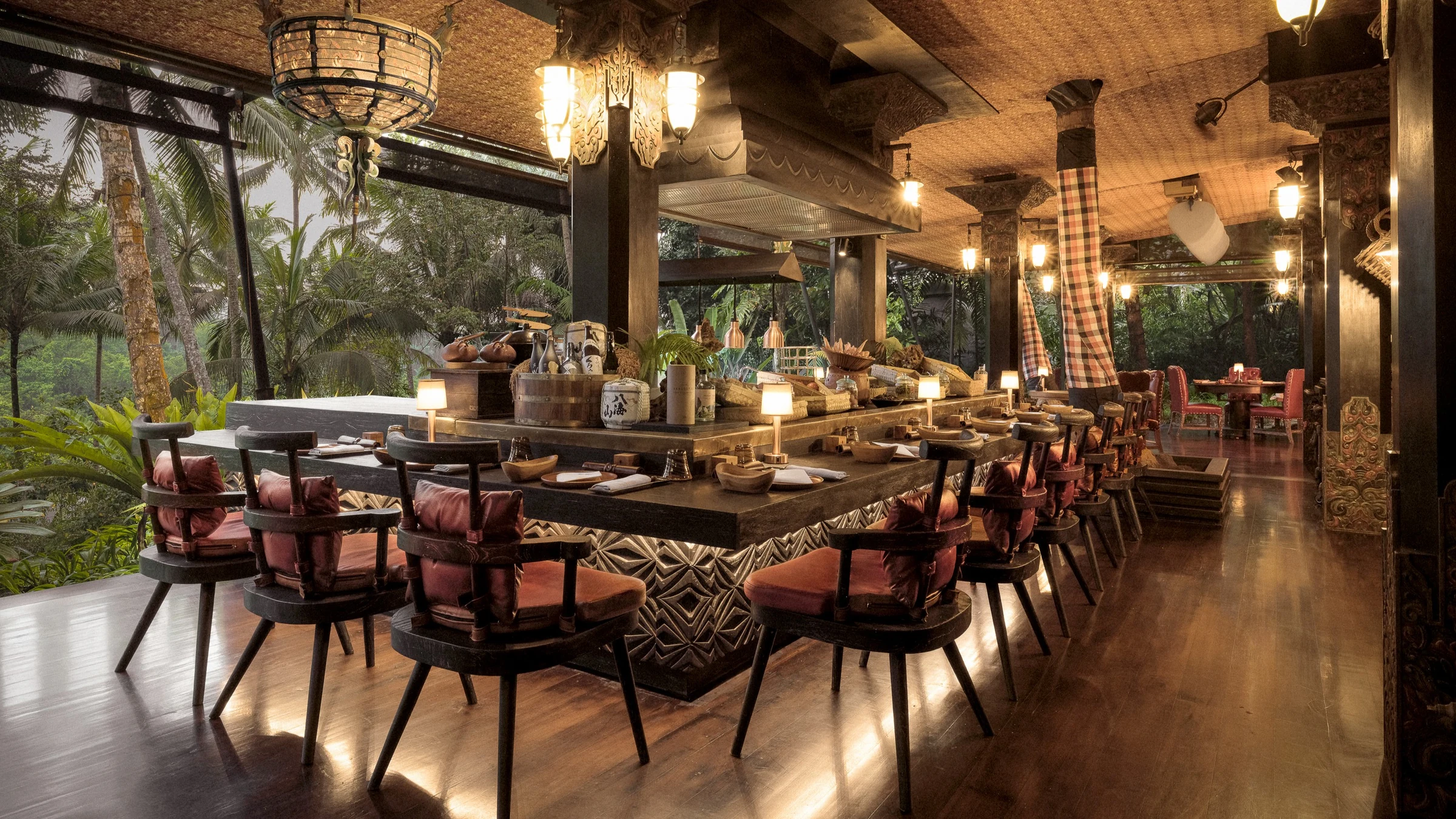 The open chef’s counter at Api Jiwa, surrounded by timber details and rainforest greenery