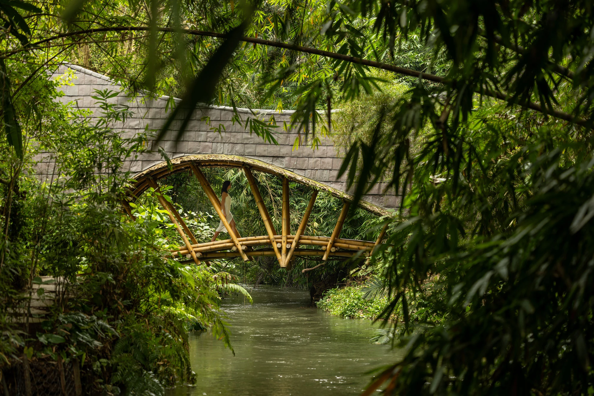 A bamboo pavilion above water, framed by thick tropical foliage at Bambu Indah.