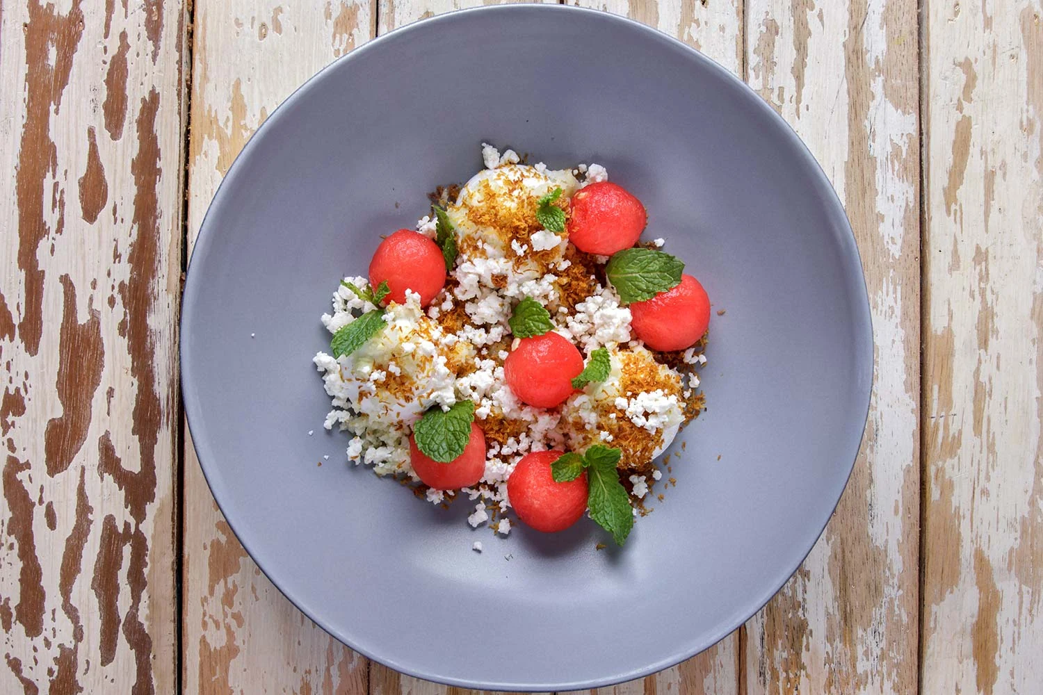 A colourful composed dish on a grey plate at Cuca