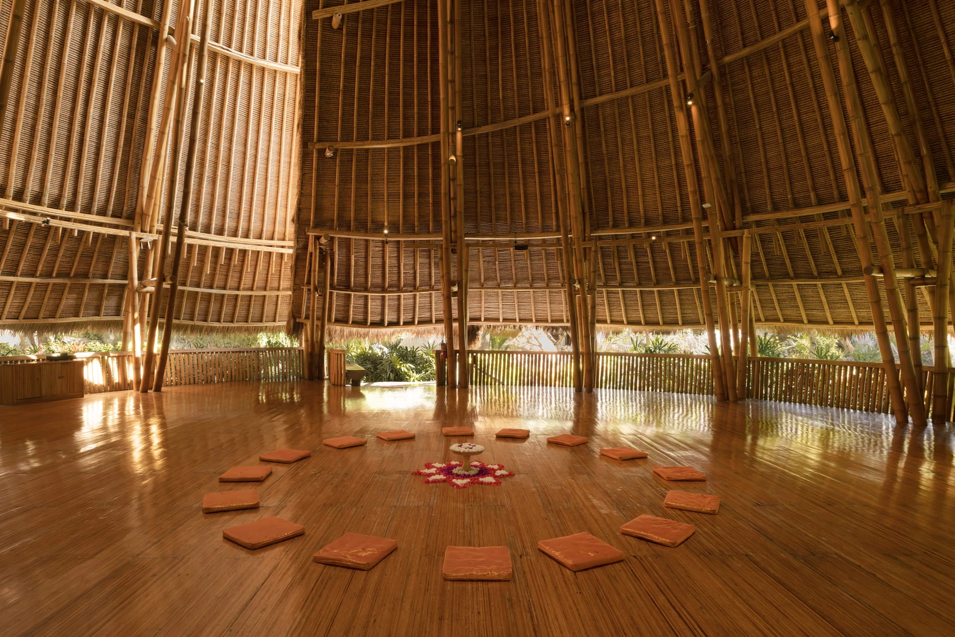 A circle of meditation cushions in a soaring bamboo pavilion at Fivelements.