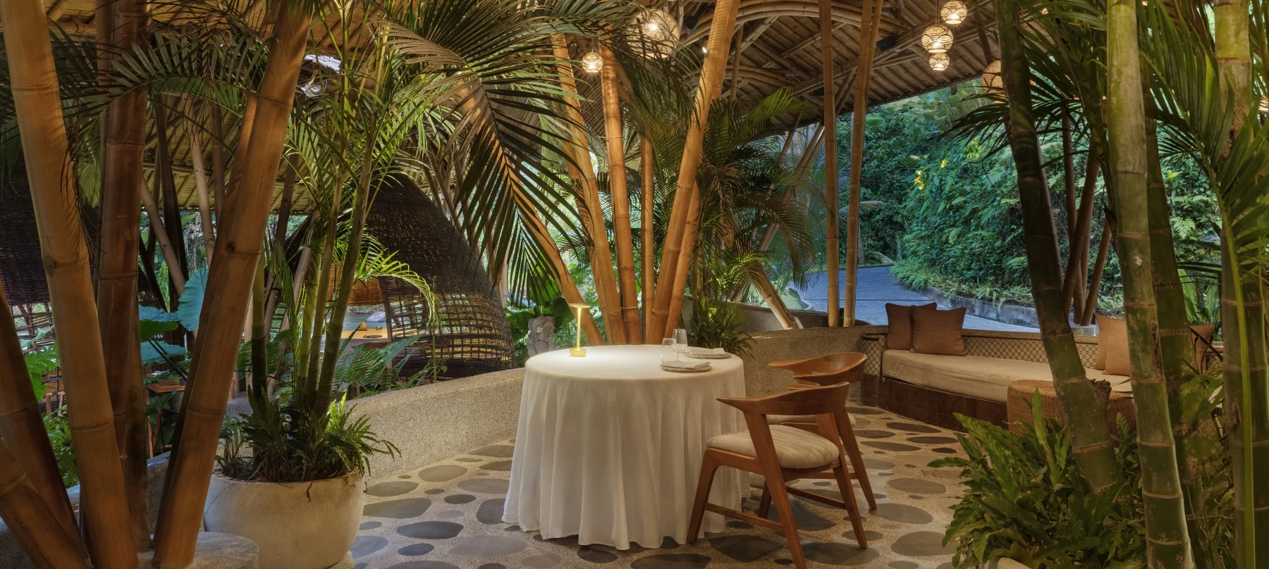 Kubu bamboo dining pavilion with a linen-covered table and views towards the river