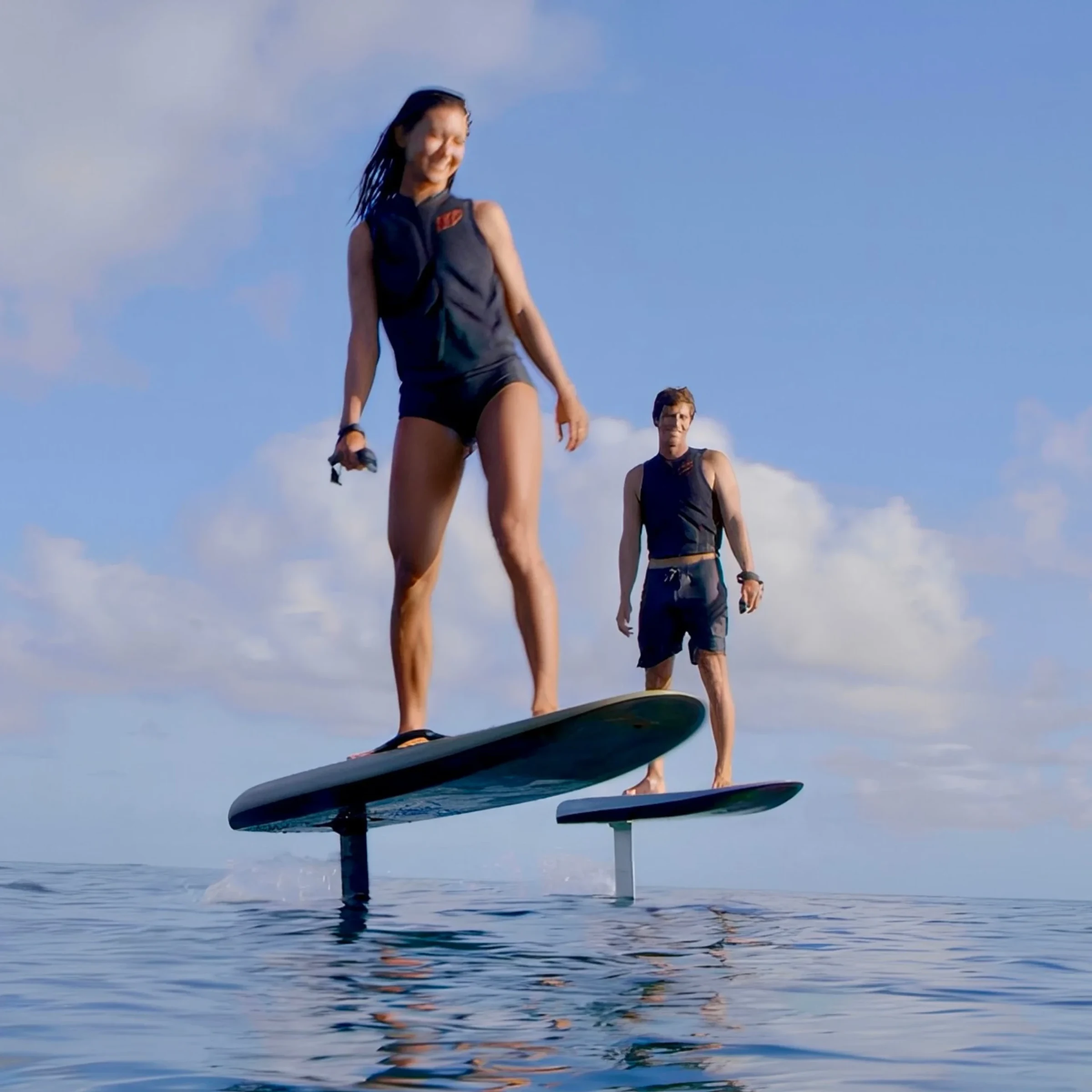 Two riders glide above the sea on electric hydrofoil boards