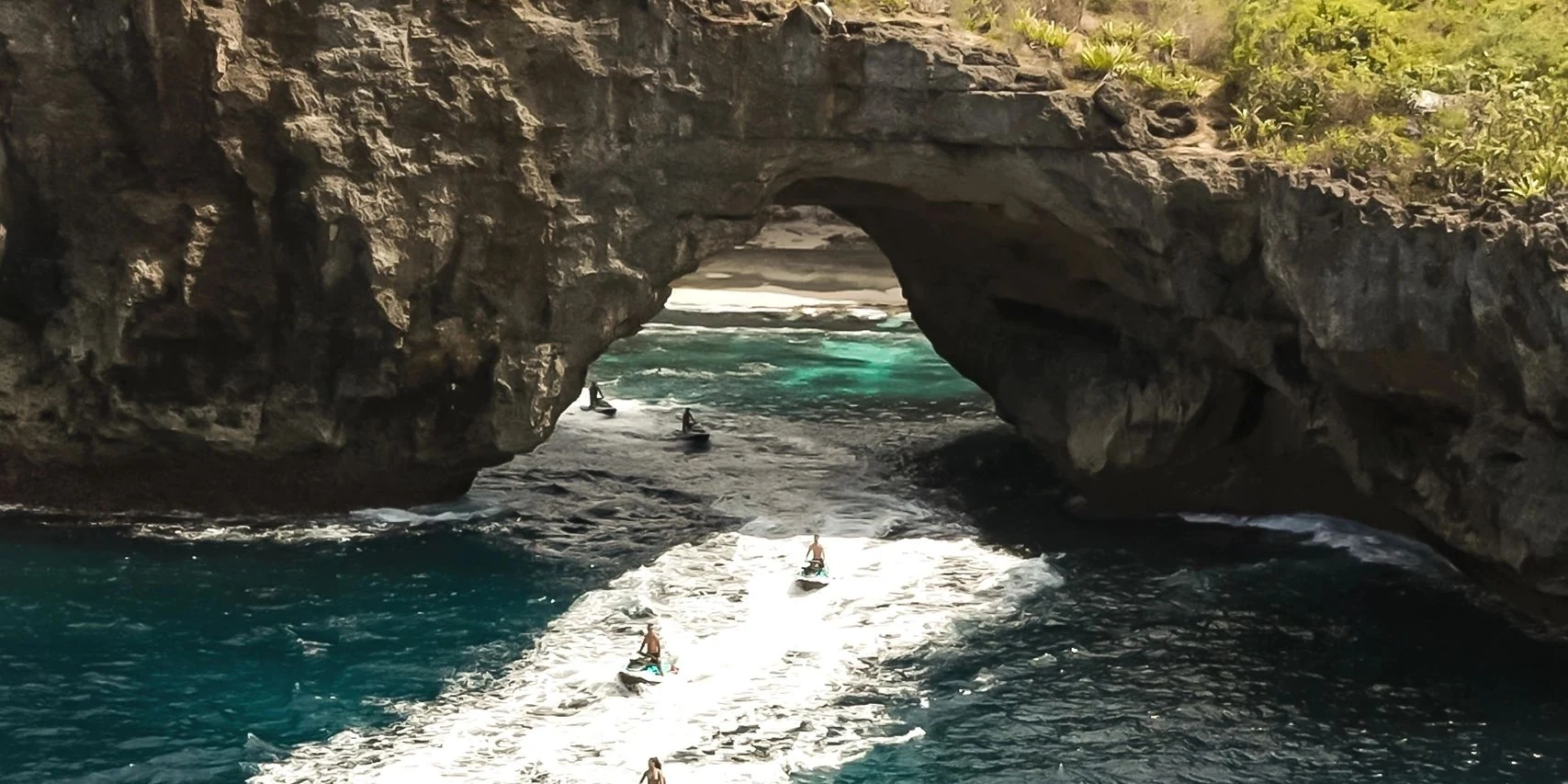 A jet ski passing the rock arch at Broken Beach on Nusa Penida