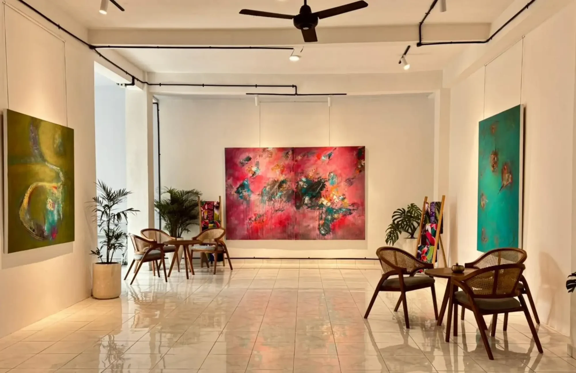 Light-filled gallery interior at Five Arts Atelier with a large contemporary painting and wooden seating.