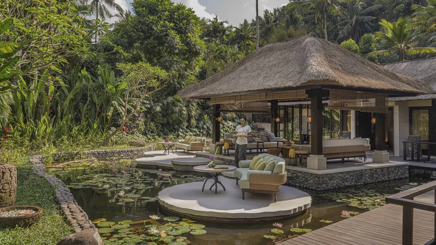 A Sacred River Spa pavilion and terrace surrounded by tropical greenery and a reflective water garden.