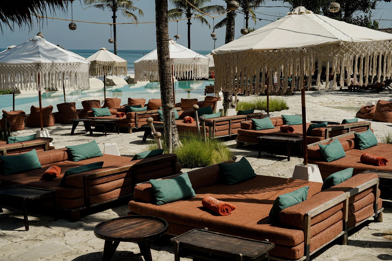 Timber lounge seating beneath white parasols at Mari Beach Club.