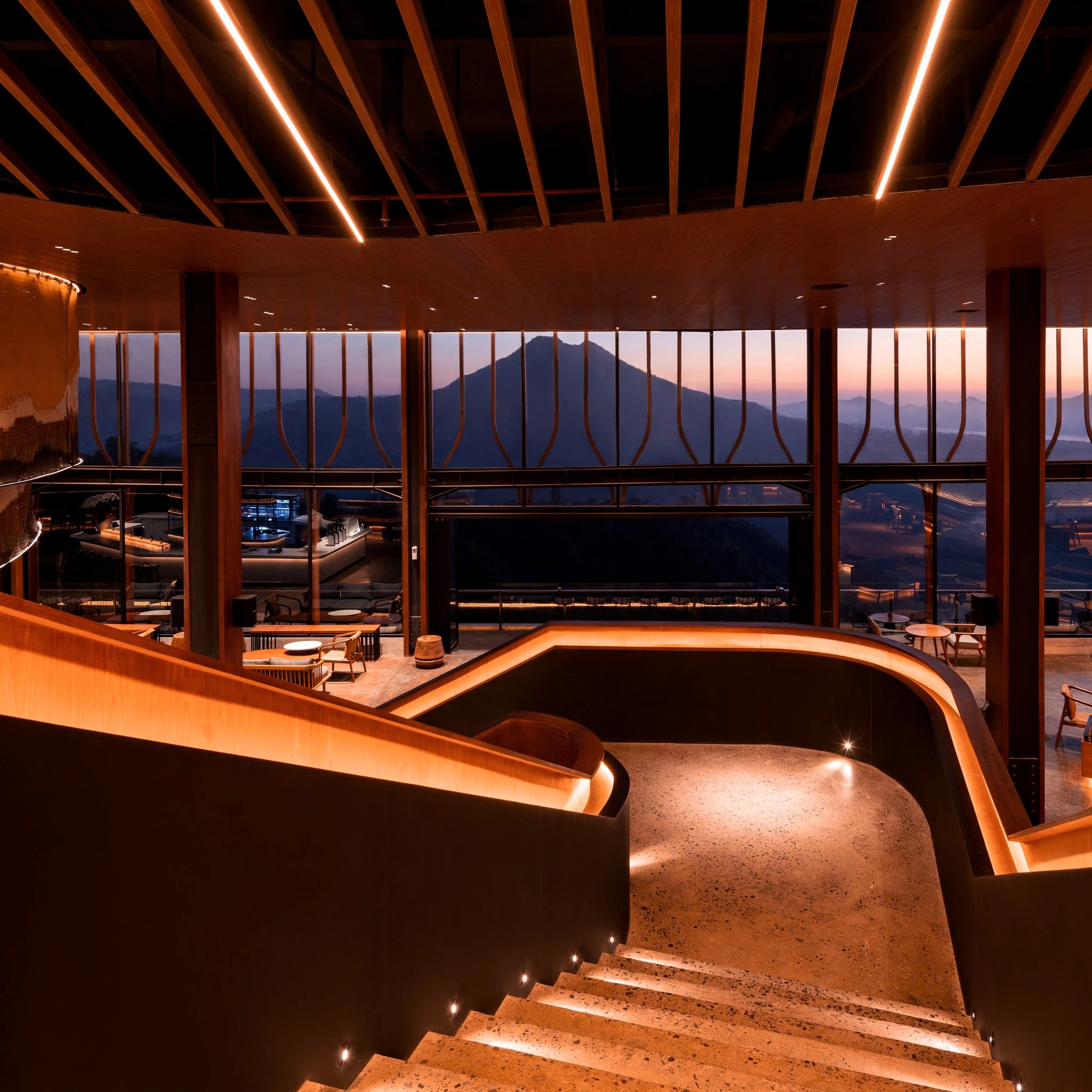 Warmly lit stairs and glass walls frame a mountain view at Pahdi Specialty Coffee in Kintamani.