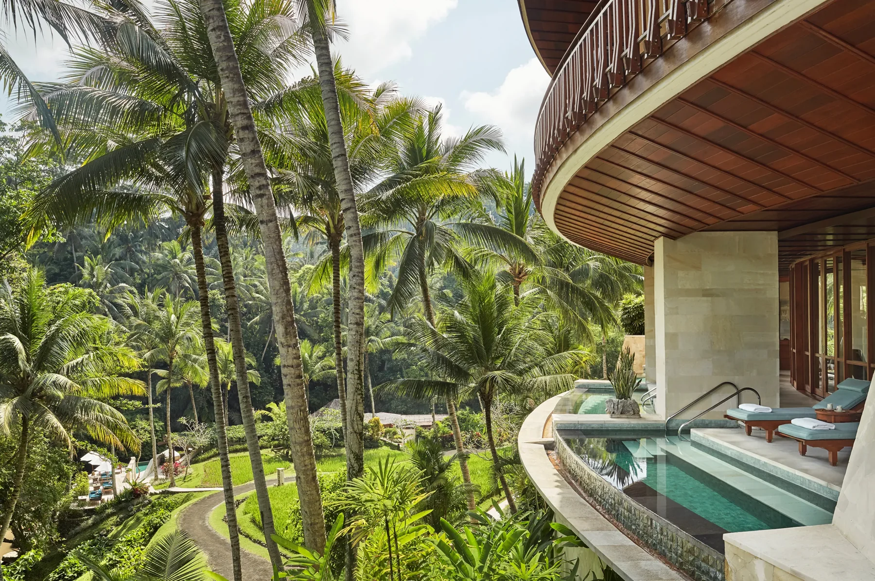 A curved spa whirlpool terrace overlooks palms and dense tropical foliage at Sacred River Spa, Four Seasons Resort Bali at Sayan.