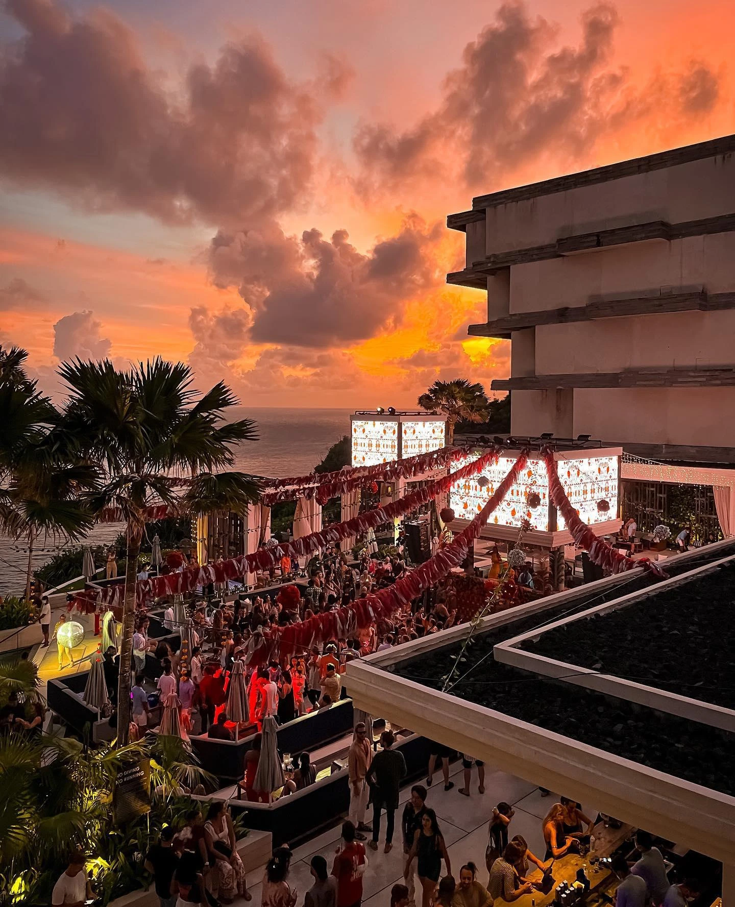 Guests on Savaya terraces beneath an orange sunset sky.