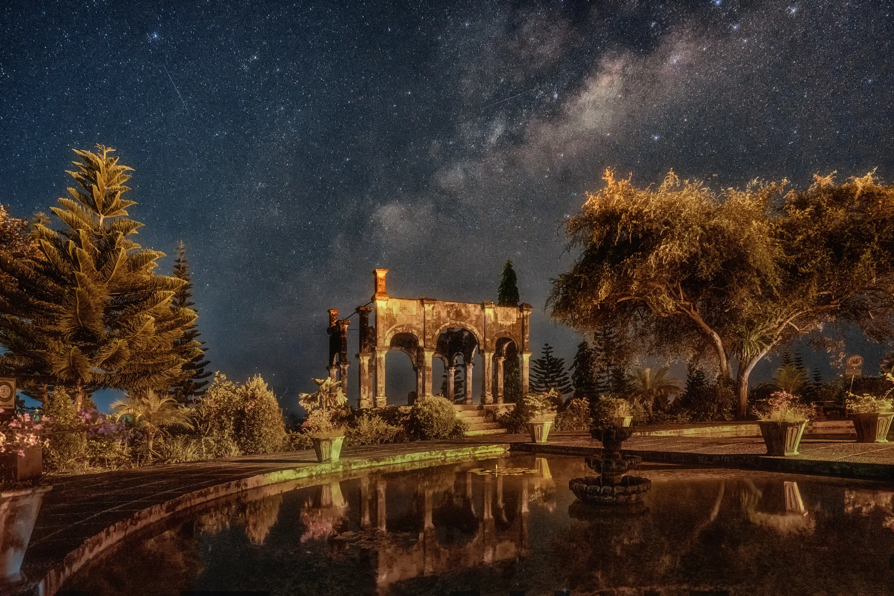 Bale Kapal at Ujung Water Palace is reflected in a pool beneath a star-filled night sky.