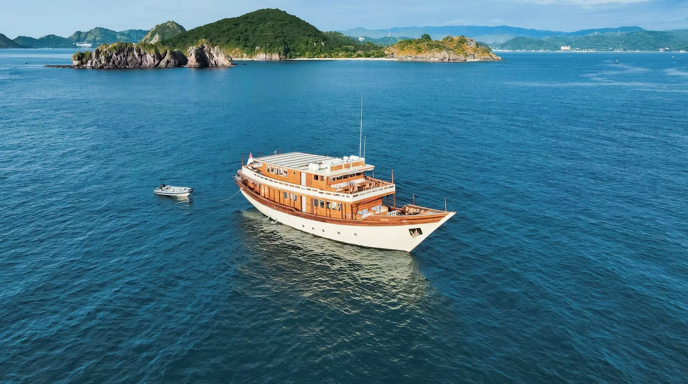 Mischief at anchor in blue water near green islands
