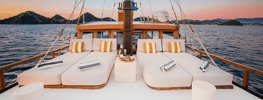 Samara II foredeck sunbeds with yellow-striped cushions at sunset