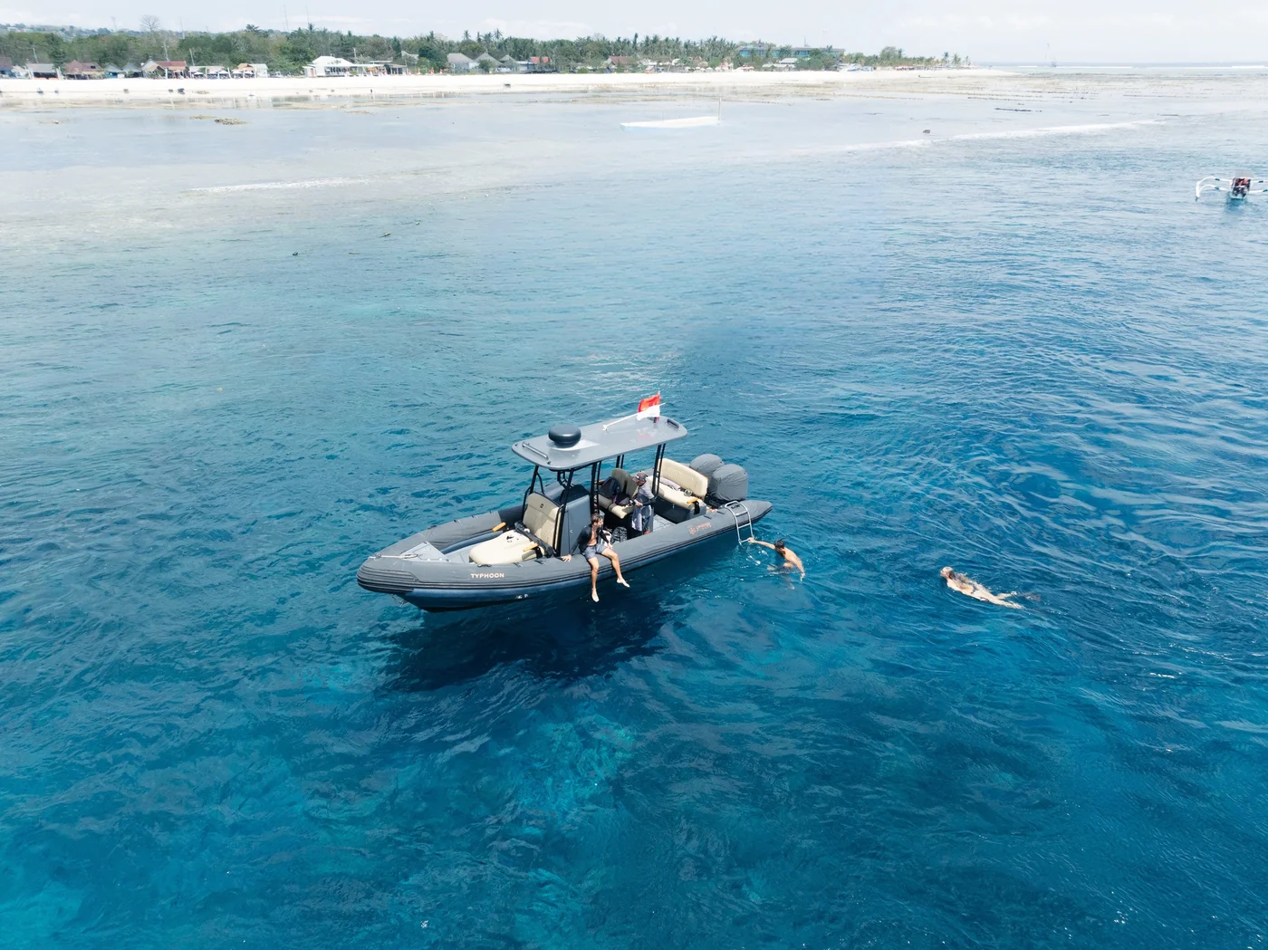Typhoon anchored in clear water beside swimmers